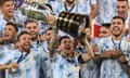Argentina's Lionel Messi holds the trophy as he celebrates on the podium with teammates after winning the 2021 Copa América