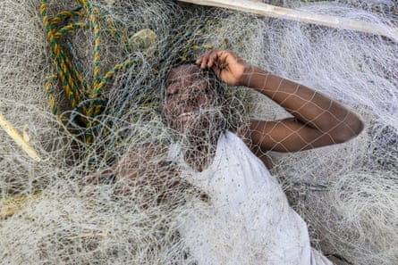 A boy smiles at the cmaeria through a fishing net