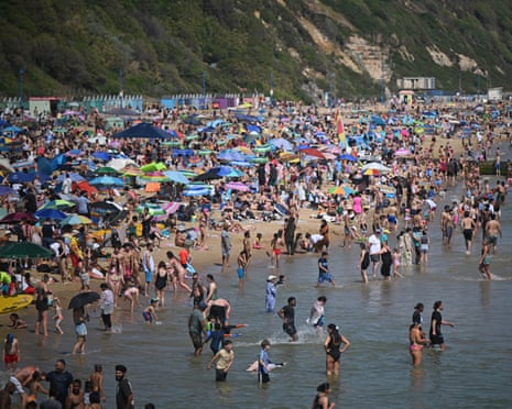 A large crowd of people on a beach, with many people in the sea
