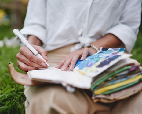 Close-up of hands writing in notebook with pen