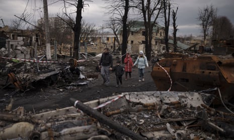 A family walks amid destroyed Russian tanks in Bucha, on the outskirts of Kyiv, Ukraine.