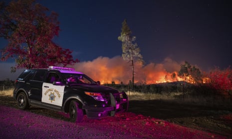 A California Highway Patrol officer watches flames that are visible from the Zogg Fire on Clear Creek Road near Igo, Calif., on Monday, Sep. 28, 2020. (AP Photo/Ethan Swope)