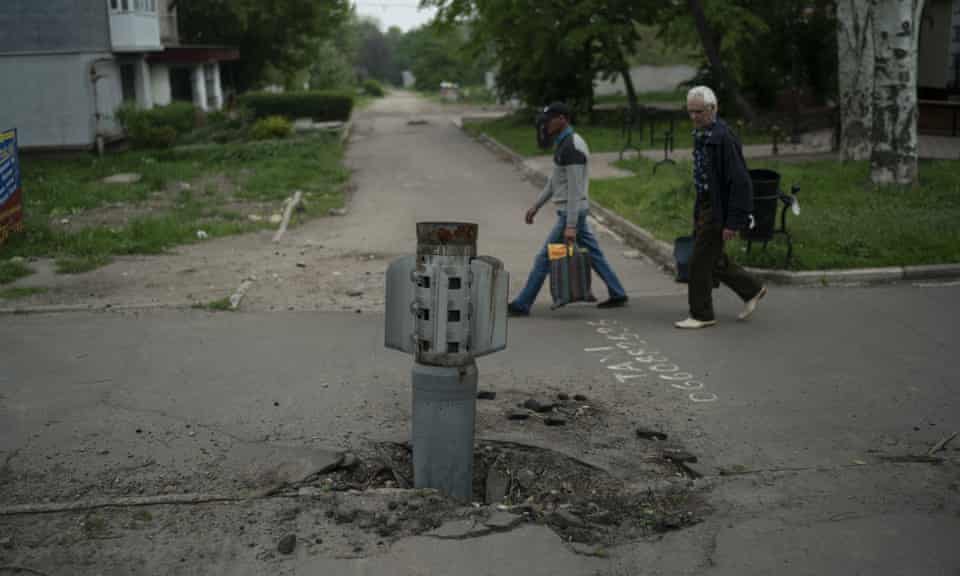 People walk past part of a rocket that wedged on the ground in Lysychansk in Luhansk region on Friday.
