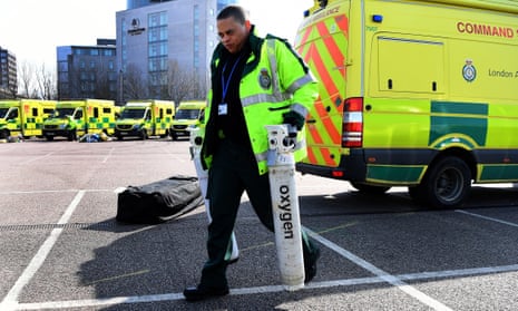 An ambulance worker unloads oxygen tanks outside the ExCel centre in London, which is being converted into a temporary hospital.
