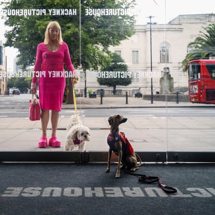 Lynne and her dog, Blue, seen through the window of the Hackney Picturehouse in London; inside is Elias, a greyhound in a Superman outfit