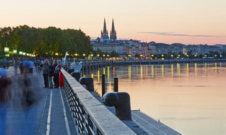 The shoreline of Bordeaux, the Garonne River with the twin towers of the ‘Eglise Saint Louis des Chartrons’ at sunset.