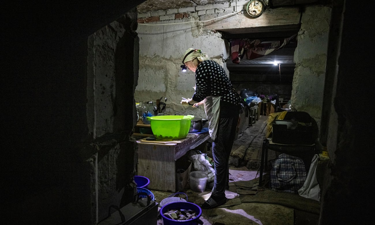 Alla Lisnenko peeling aubergine in the basement using a flashlight.