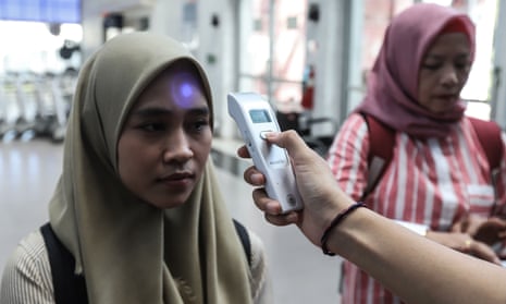 Passengers have their temperatures checked at a train station in Palembang, Indonesia.