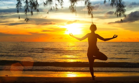 Young woman practising yoga at sunset