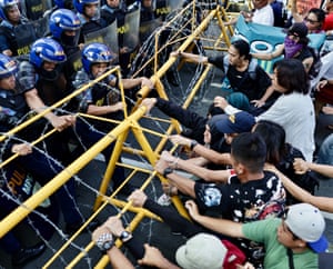 Anti-Marcos protesters pull barriers at a demonstration in Manila