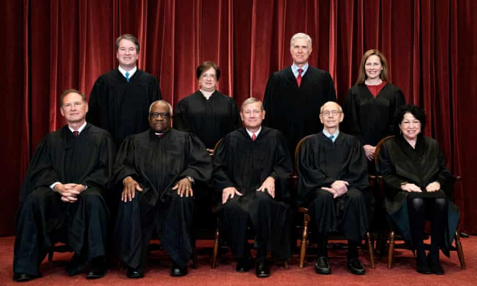 US supreme court justices sit in front of a red curtain at the Supreme Court. 
