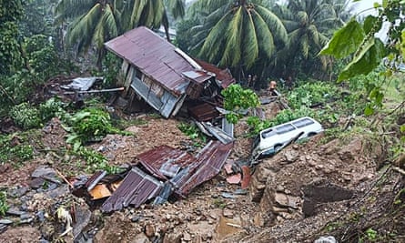 A resident beside a damaged house and vehicle after a landslide in Parang town in Maguindanao province, southern Philippine