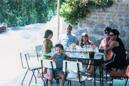 Fiona Collier, who lost her parents and sister in a helicopter crash, sitting round a table in Portugal in 1967 with er parents, sisters and grandmother