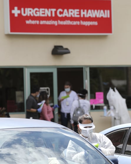 A medical worker talks to a person in their car outside an Urgent Care Hawaii medical clinic, which is offering drive through testing for the coronavirus.