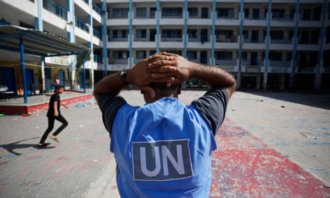 A man with his back to the camera wearing a blue vest with the UN logo on the back