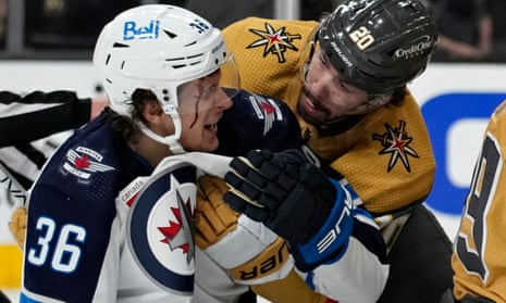 Vegas Golden Knights center Chandler Stephenson (20) helps Winnipeg Jets center Morgan Barron (36) after Barron cut his face on a skate during the first period of Tuesday’s Game 1.