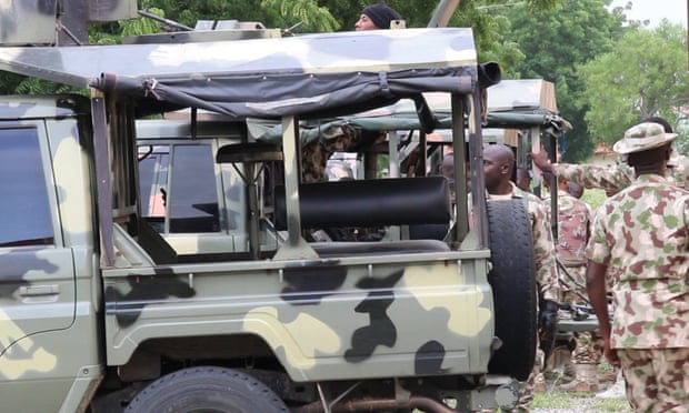 Nigerian soldiers stand beside truck