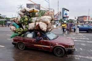 Yaounde, Cameroon: a motorist drives a car loaded high with vegetables and fruit