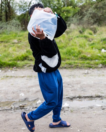 A Vietnamese man carrying a water bladder at a makeshift camp in Loon-Plage, near Dunkirk.