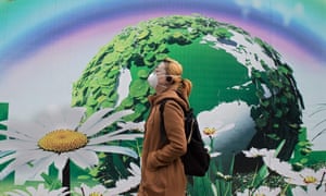 A woman wearing a protective pollution mask walks past a billboard in Beijing