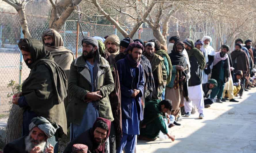 Afghans wait for hours to receive food aid.