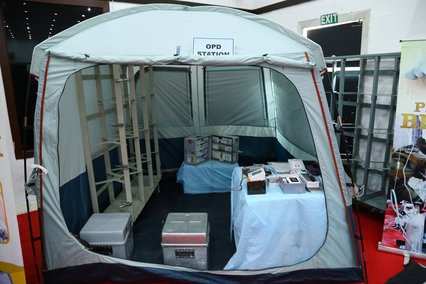 A tent with metal boxes and tables covered in medical supplies inside A tent with metal boxes and tables covered in medical supplies inside