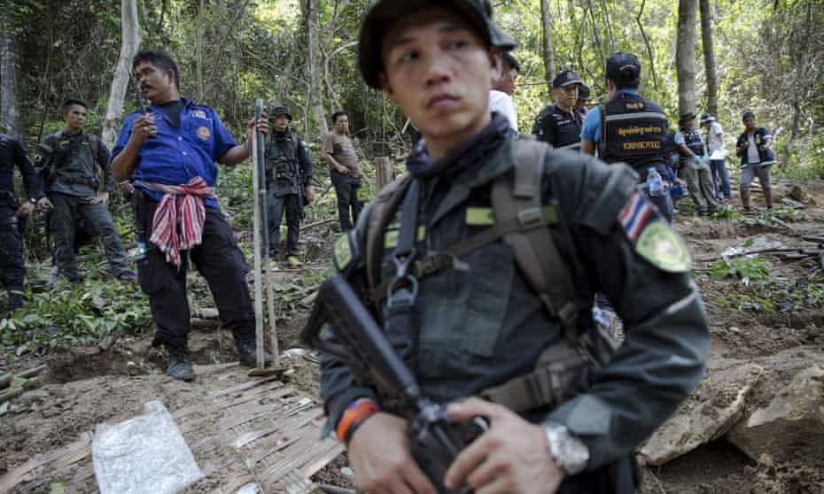 Security forces and rescue workers watching as bodies of trafficked refugees are retrieved from a mass grave in Thailand’s southern Songkhla province.
