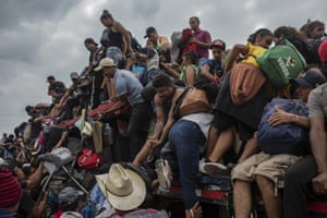 Migrants help fellow migrants onto the bed of a trailer in Jesus Carranza.