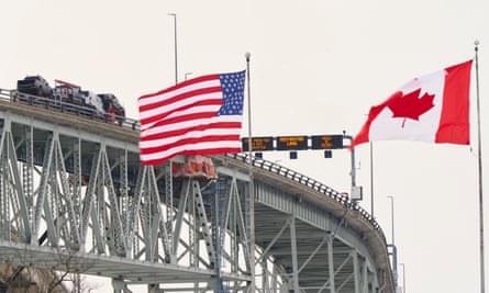 The US and Canadian flags fly on the US side of the St Clair River, near the Bluewater Bridge border crossing between Sarnia, Ontario and Port Huron, Michigan