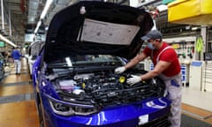 A worker inspects under the bonnet of a Volkswagen Golf 8 automobile on the assembly line at the Volkswagen factory in Wolfsburg, Germany, in 2021.