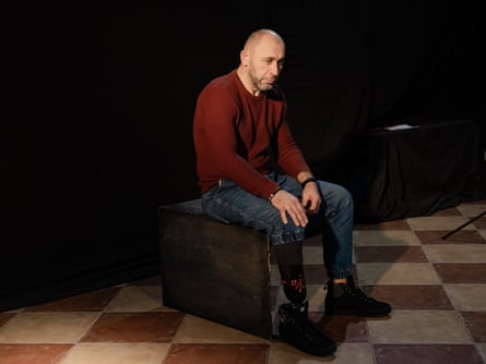 A middle-aged man pinch a prosthetic limb sits successful a darkened room staring into space