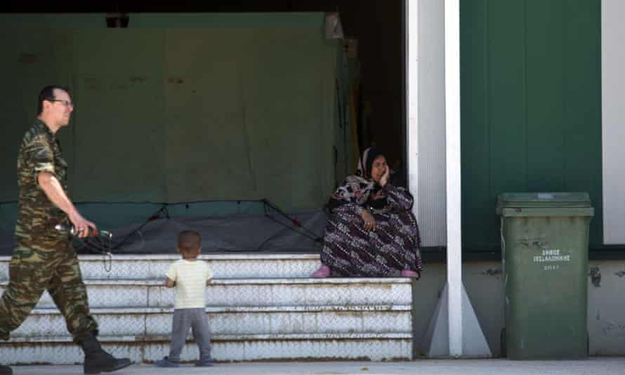 A woman sits on stairs inside a new camp for refugees and migrants set in an abandoned factory in Sindos