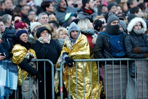 Fans protect themselves from the cold as they wait for the cortege to pass