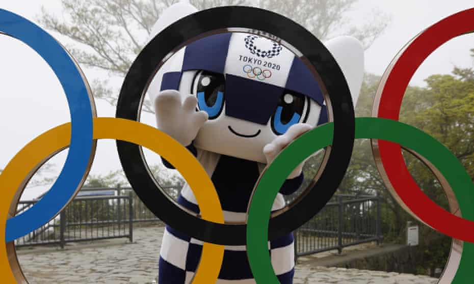 The Tokyo 2020 mascot poses with the Olympic rings. 