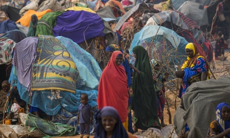 People walk through a displacement camp outskirts of Dollow, Somalia, on Monday, Sept. 19, 2022. Somalia is in the midst of the worst drought anyone there can remember. A rare famine declaration could be made within weeks. Climate change and fallout from the war in Ukraine are in part to blame. (AP Photo/Jerome Delay)