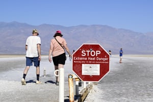 Tourists walk past a stop sign warning of extreme heat