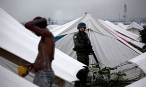 A UN soldier watches a man washing in a refugee camp of Cité Soleil, Port-au-Prince. Sanitation and sewage dispoal was so poor at UN military bases that it ‘will potentially damage the reputation of the mission’, according to the report.