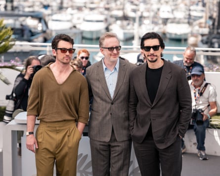 Miles Teller, James Gray and Adam Driver pose for the cameras at the Cannes harbour front. Teller wears a light brown V-necked jumper and pleated-front trousers while Gray and Driver wear greyish suits.