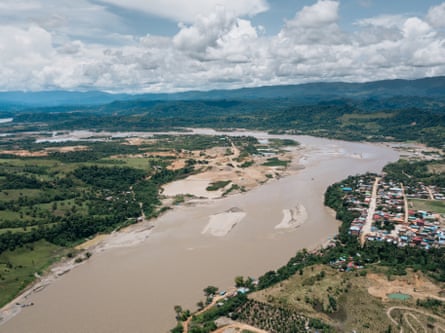 An aerial shot of a wide, muddy river passing through a town.