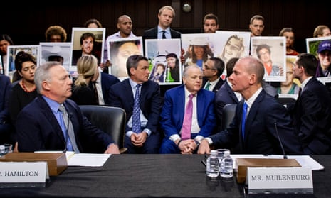 Denis Muilenberg, right, at the hearing in Washington on Wednesday, as family members of the victims who died in the crashes hold pictures of their loved ones.