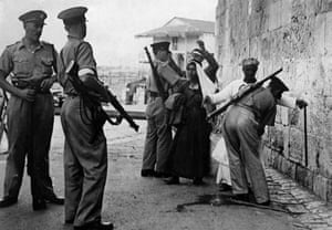 British soldiers searching Arabs for weapons as they enter Jerusalem in 1938.