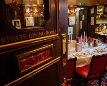 A slightly ajar private dining room showing a table lined with plates and cutlery