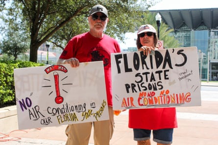 People hold signs at a rally demanding Florida legislators do something about the lack of air conditioning inside state-run prisons.