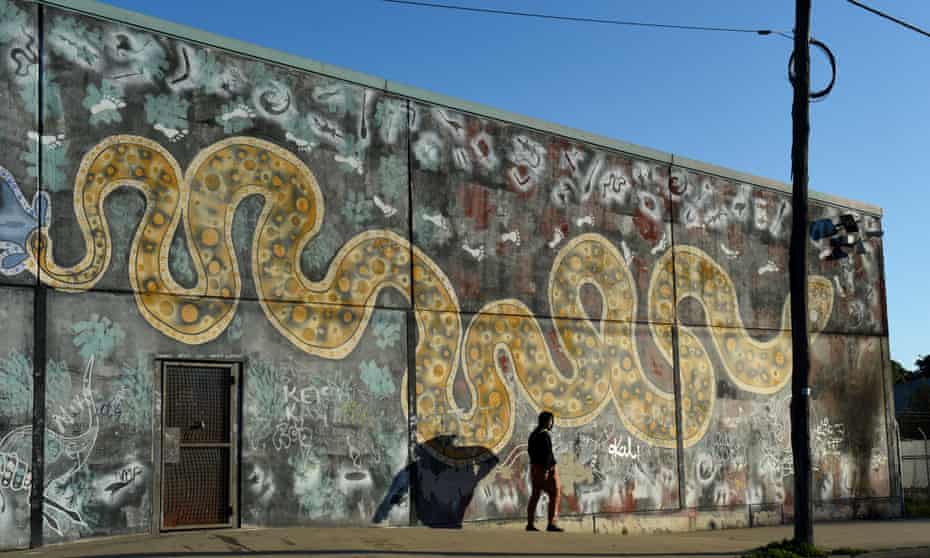 A young man walks past a mural of the rainbow serpent in the NSW town of Bourke