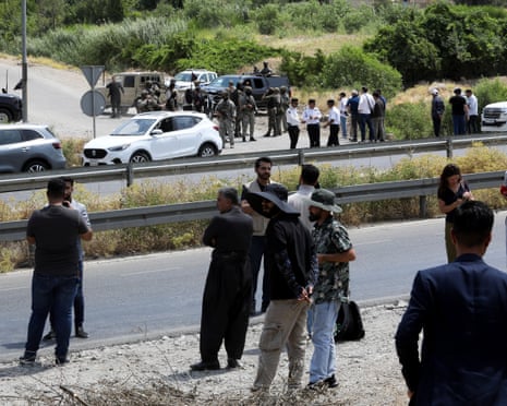People gather as Kurdish security forces stand at a checkpoint, on the day of a disarmament ceremony of Kurdistan Workers' Party (PKK) fighters, marking a significant step toward ending the decades-long conflict between Turkey and the outlawed group, near Sulaymaniyah, Iraq, July 11, 2025.