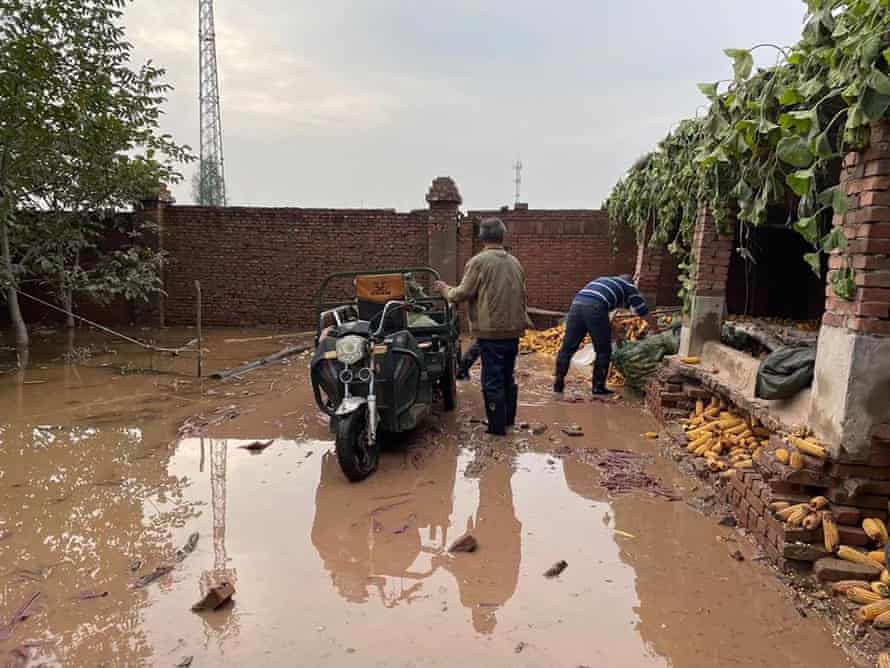 Luo Qiang and her father attempt to move flooded corns to a dry place.