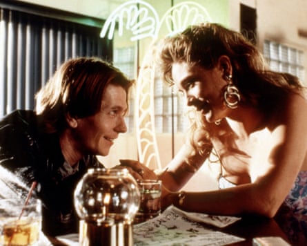 A still from 1988 film Gary Oldman and Theresa Russell leaning across a table and looking at each other in the eye.