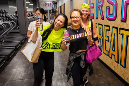 A group of middle-aged women in neon gym clothes, smiling as they leave a dance class.