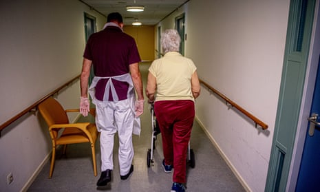 Male carer walking down a corridor with a female care home resident