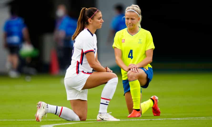 Alex Morgan of the United States and Hanna Glas of Sweden take a knee before their football match at Tokyo Stadium.